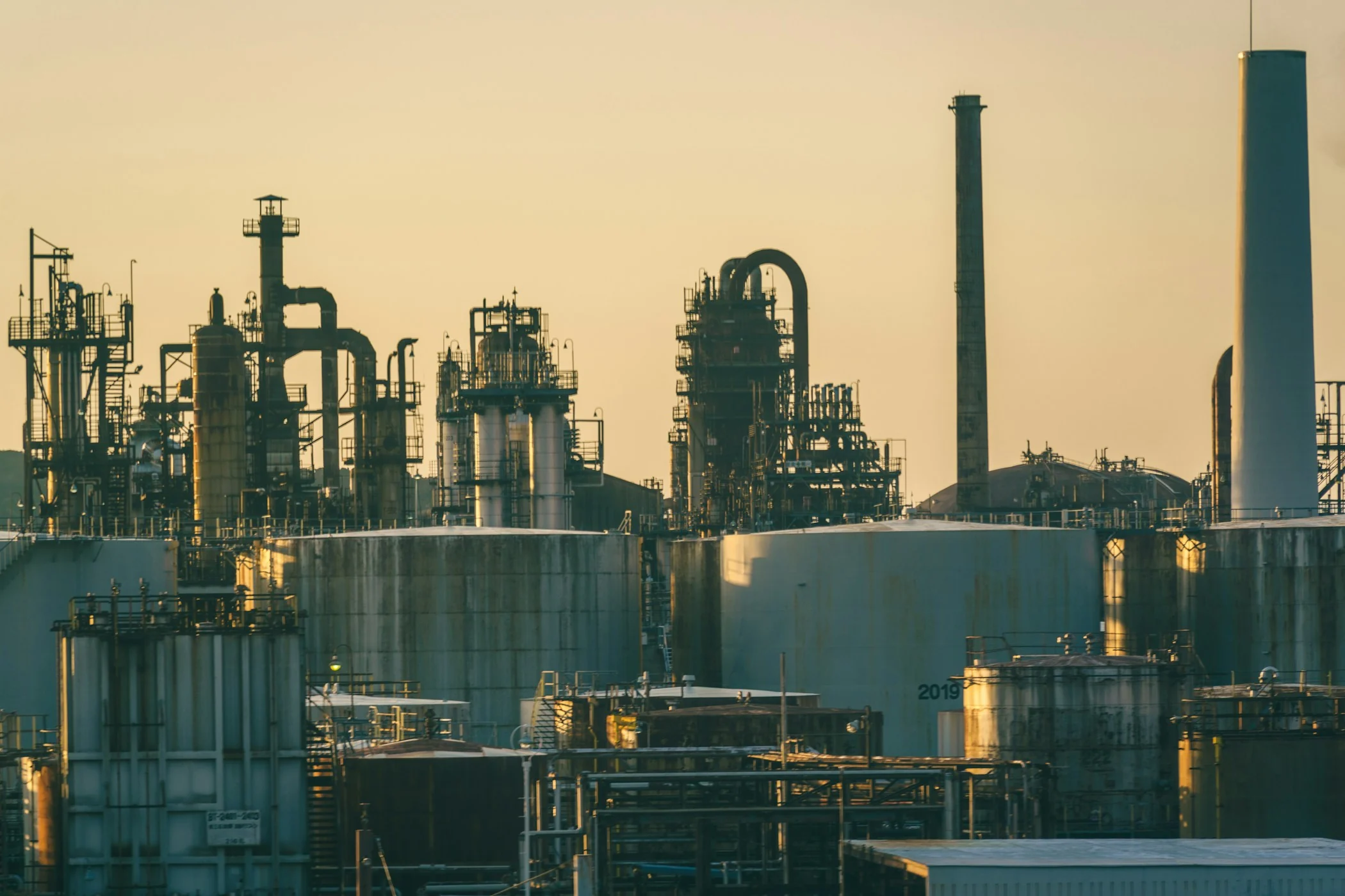Process plant towers, storage tanks and industrial infrastructure at sunset